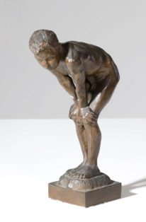 Dreng, der støtter hænderne mod de bøjede knæ